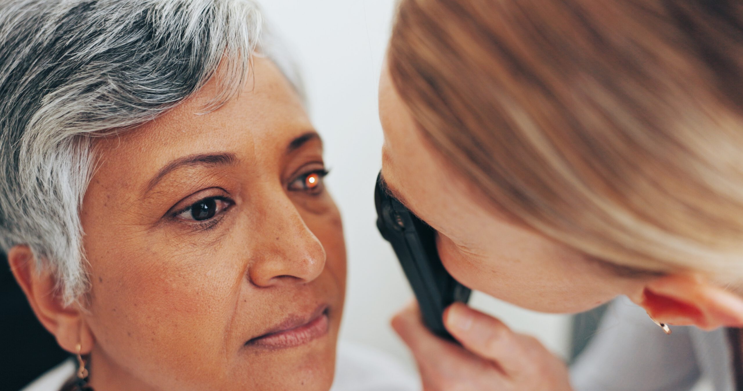 Clinician closely examining the eyes of a senior patient